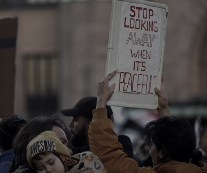 Joukkojoukossa oleva henkilö pitää pystyssä kylttiä, jossa lukee "lopeta katsomasta pois, kun se on rauhallista", ja se välittää koskettavan viestin apatiaa vastaan rauhallisina aikoina.