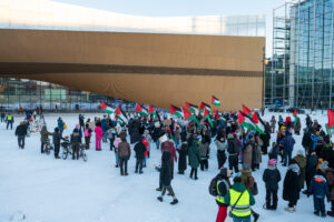 Mielenosoittajia Keskuskirjasto Oodin edessä, talvisena päivänä, heiluttaen monia Palestiinan lippuja